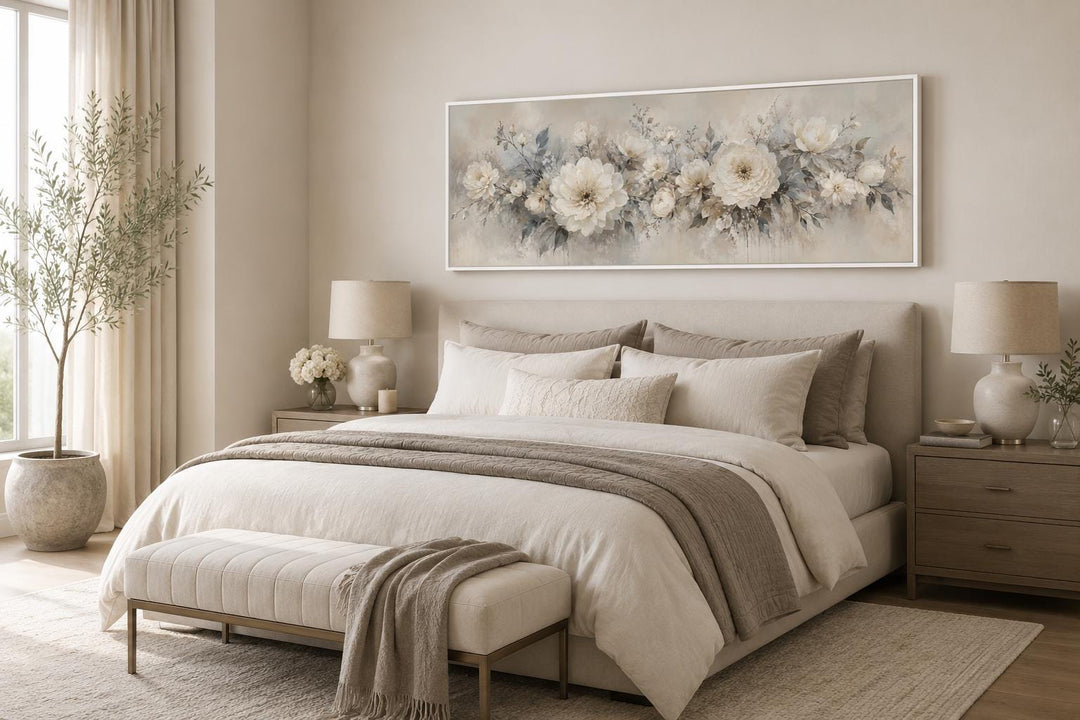 Long horizontal canvas print of white peonies in a neutral bedroom above a bed.