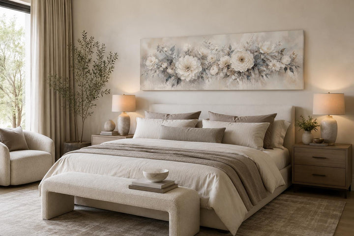 Long horizontal canvas print of white peonies in a neutral bedroom above a bed.