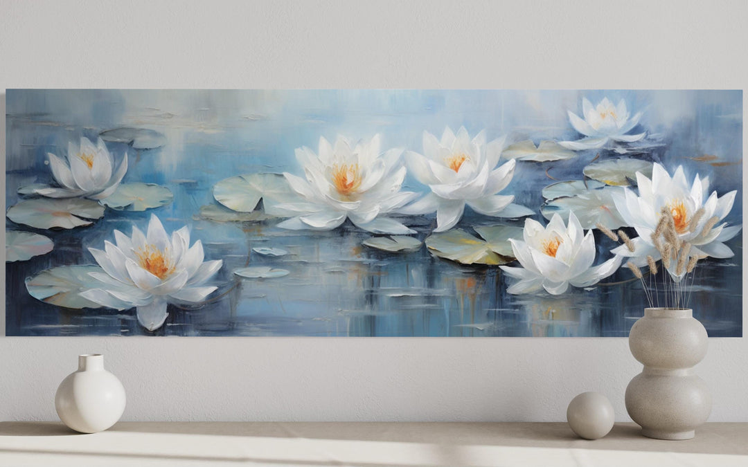 Horizontal canvas wall art of white lotus flowers floating on blue water above a neutral shelf.