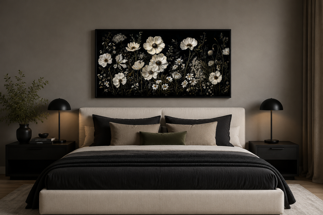 Moody framed canvas wall art featuring white wildflowers on a black background above a bed.