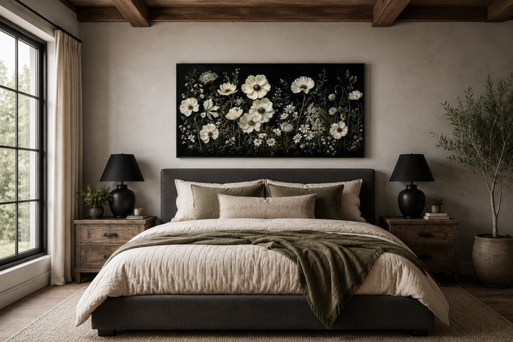 White wildflowers on black background moody framed canvas wall art hanging above a bed.