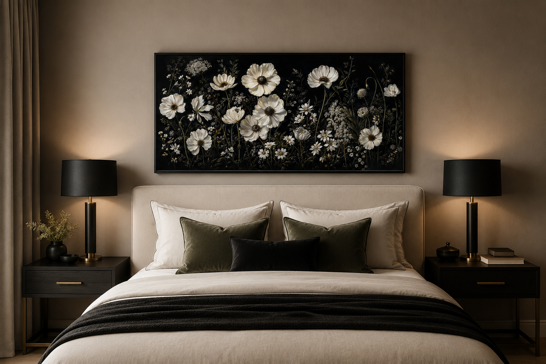 Moody framed canvas wall art featuring white wildflowers on a black background above a bed.
