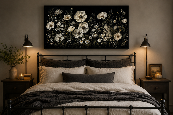 White wildflowers on black background moody framed canvas wall art hanging above a bed.
