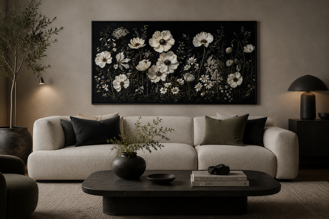 Moody framed canvas wall art featuring white wildflowers on a black background above a white sofa.