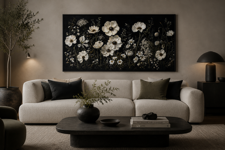 Moody framed canvas wall art featuring white wildflowers on a black background above a white sofa.