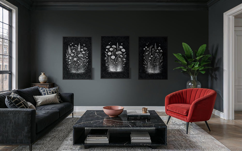 Set of three black and white wildflower canvas prints displayed on a dark gray wall in a living room.