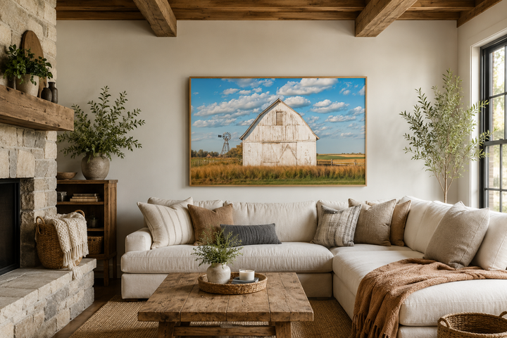 Framed canvas wall art of a weathered white barn and windmill in a rustic farmhouse living room.