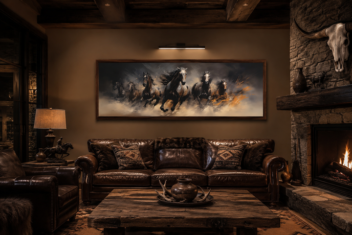 Long horizontal canvas wall art of wild brown galloping horses above a leather sofa in a rustic den.