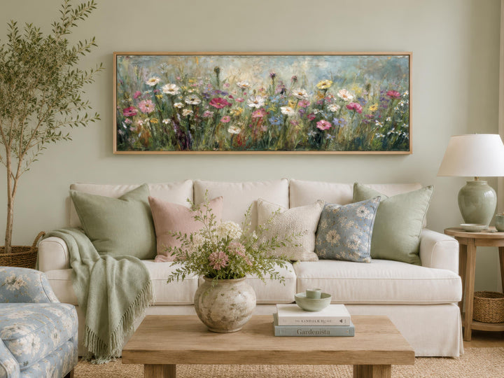 A long, horizontal canvas painting of a colorful wildflower meadow hangs above a sofa.