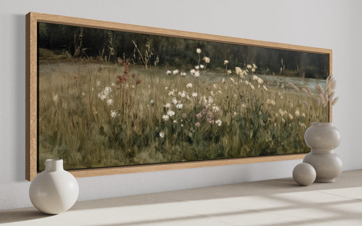 Long narrow canvas print of a wildflower meadow in neutral beige and olive tones with a wood frame.