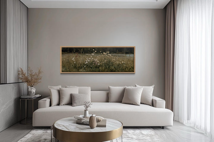 Horizontal wildflower meadow wall art in a light wood frame above a modern neutral sofa.