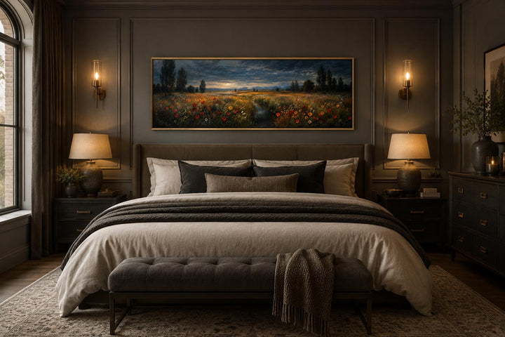 Horizontal wildflower meadow canvas print in a gold frame hanging above a bed in a moody bedroom.
