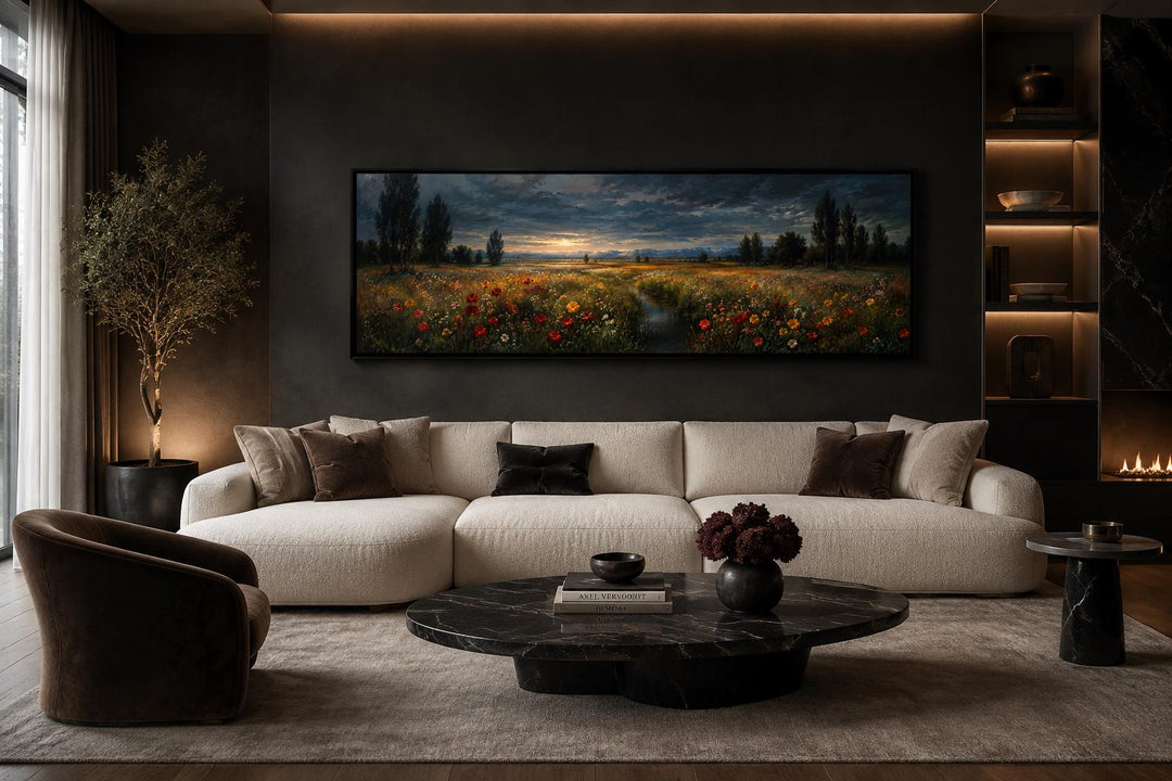 Wide horizontal canvas of a wildflower meadow at dusk with a moody sky above a modern sofa.