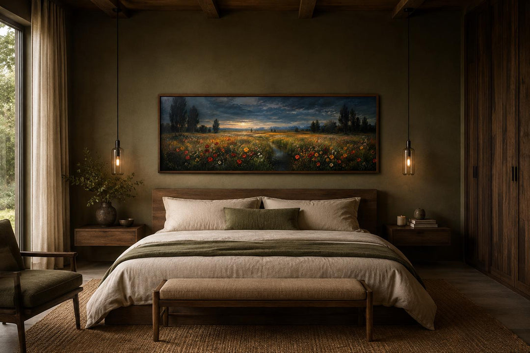 Wide horizontal wildflower meadow at dusk canvas art hanging above a bed in a moody bedroom.