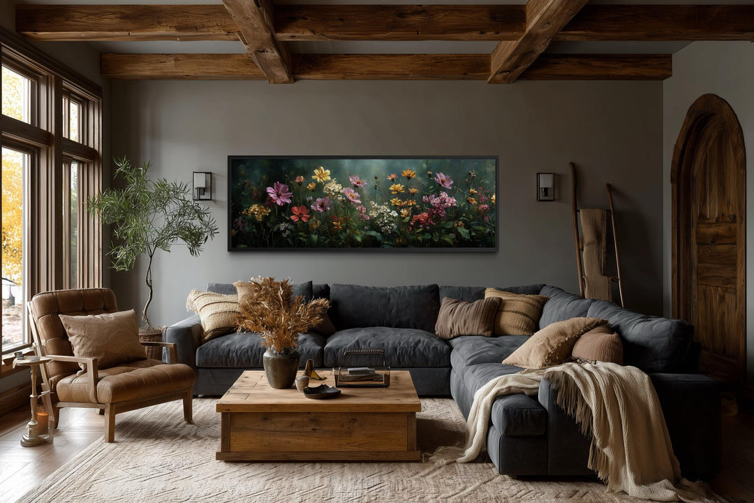A wide horizontal canvas of a wildflower meadow with a green background hangs above a dark sofa.