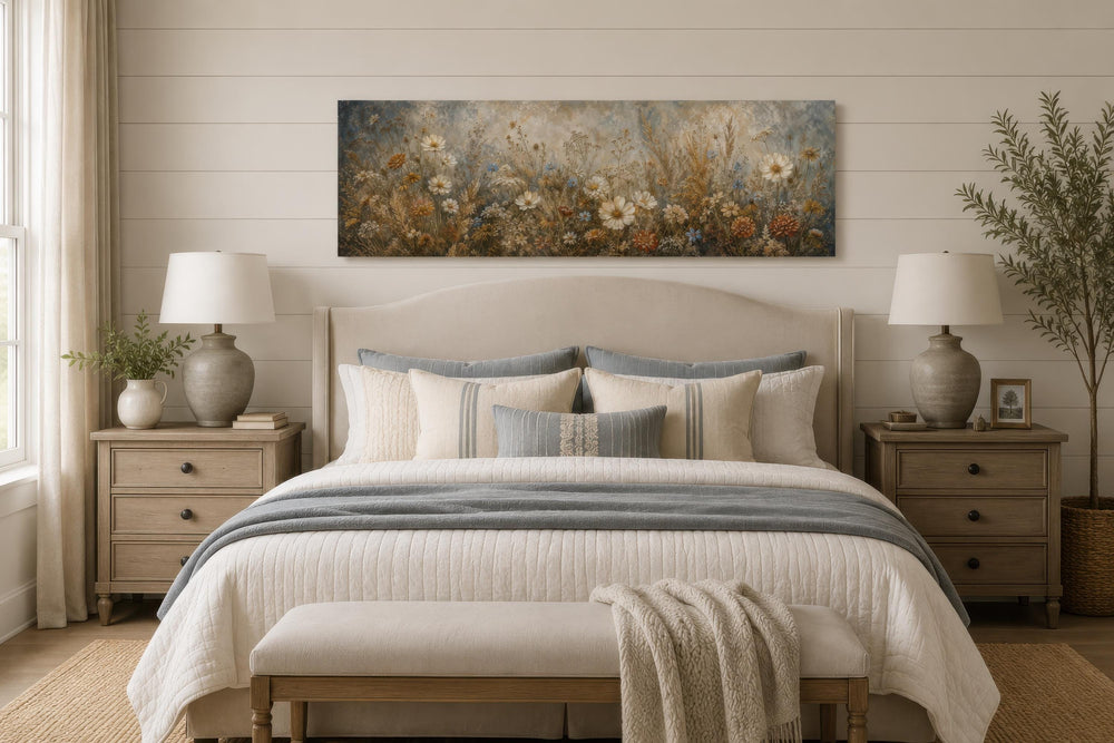 A long narrow canvas print of neutral wildflowers and daisies hanging above a bed.