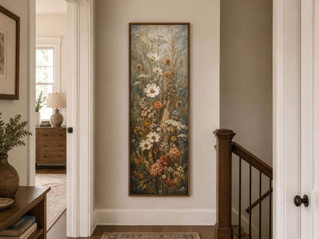 Tall vertical canvas print of wildflowers in blue, rust, and cream tones on a neutral hallway wall.