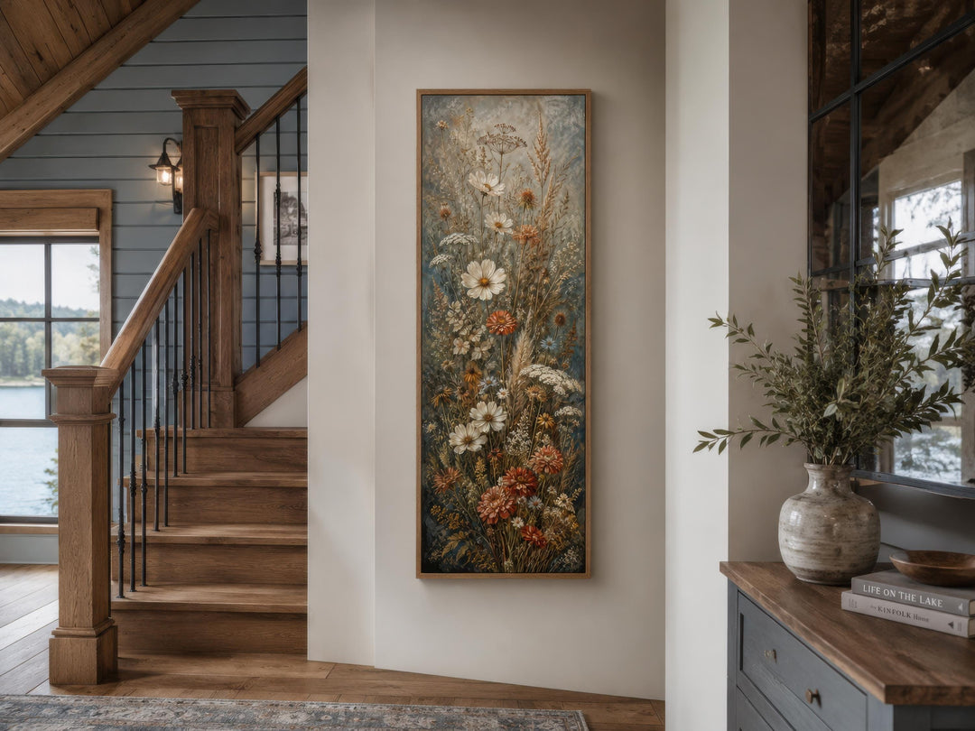 Tall vertical canvas print of wildflowers in blue, rust, and cream hanging in a rustic entryway.