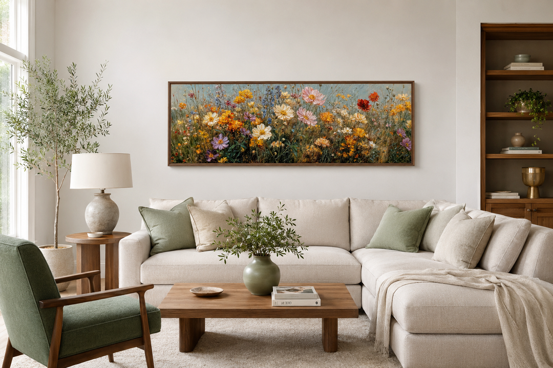 Long horizontal painting of colorful wildflowers in a wooden frame above a neutral sectional sofa.