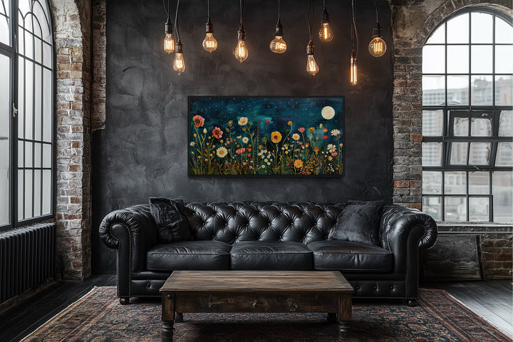 Wildflowers field at night under moon large horizontal wall art above a black leather sofa.