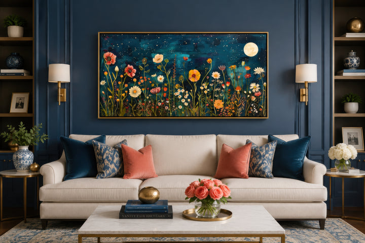 Large horizontal wall art of a wildflower field at night under a full moon above a cream sofa.