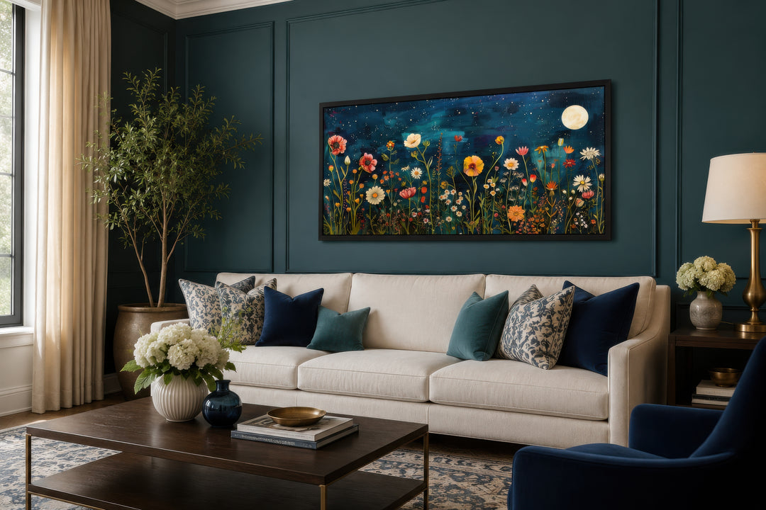 Large horizontal wall art of a wildflower field at night under a full moon above a white sofa.