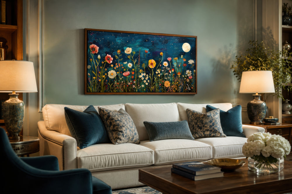 Large horizontal wall art of a wildflower field at night under a moon, framed above a white sofa.