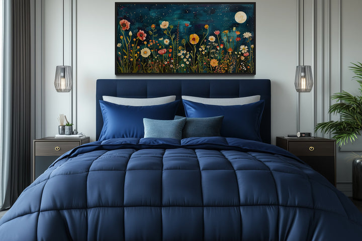 Wildflowers field at night under a moon large horizontal wall art hanging above a blue bed.