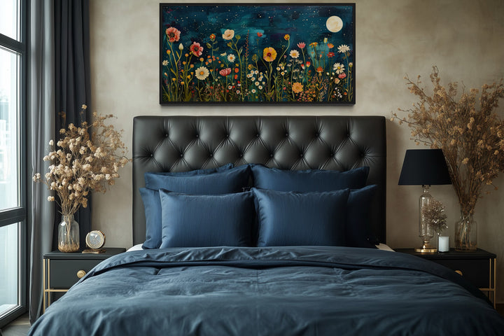 Large horizontal wall art of a wildflower field at night under a moon, hung above a tufted bed.