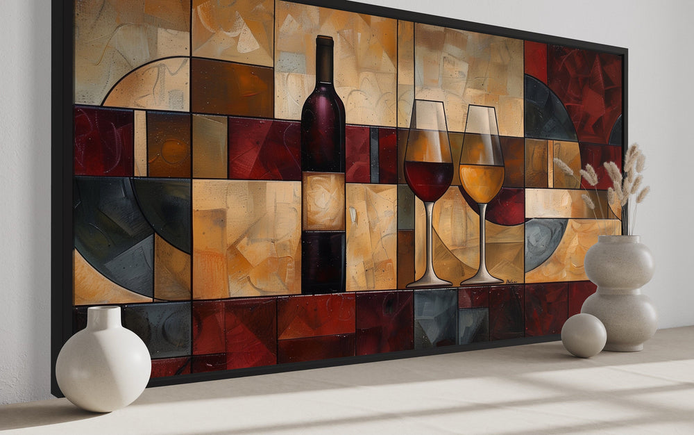 Abstract wine bottle and glasses wall art in red and gold tones on a dining room wall.