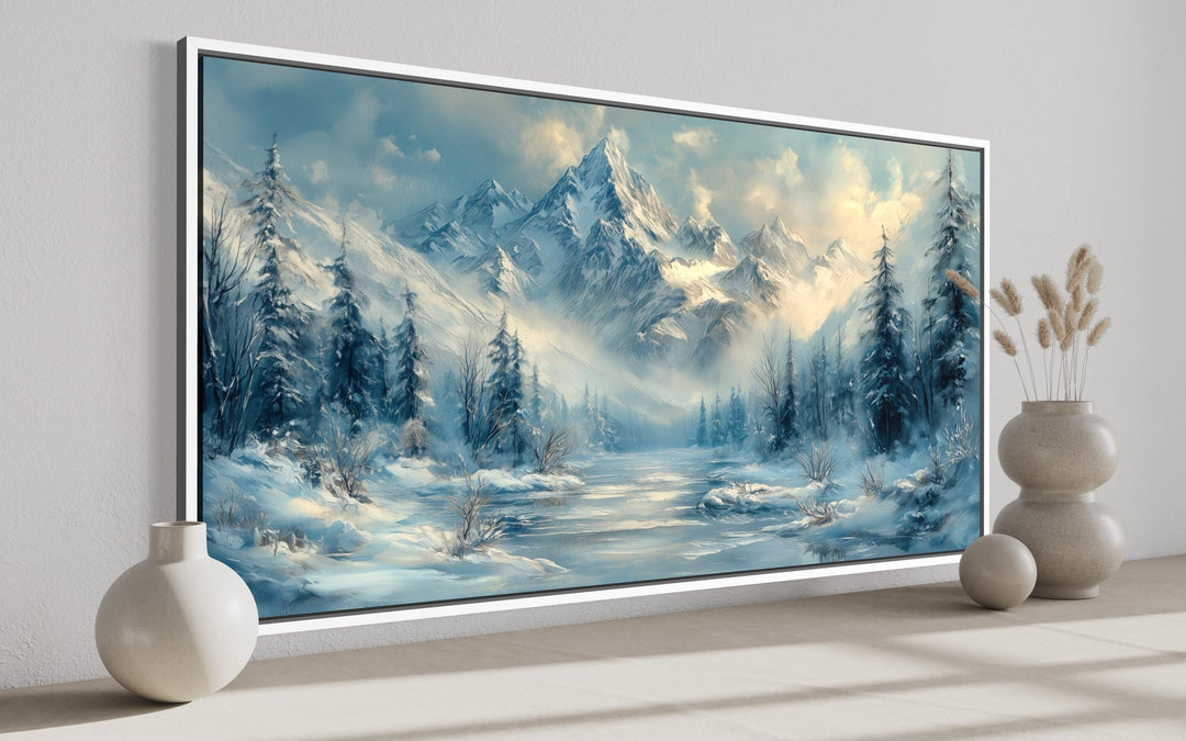 Winter mountain wall art featuring a snowy peak, frozen lake, and alpine trees in a white frame.