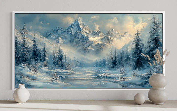 Winter mountain wall art featuring a snowy peak, frozen lake, and alpine trees in a white frame.