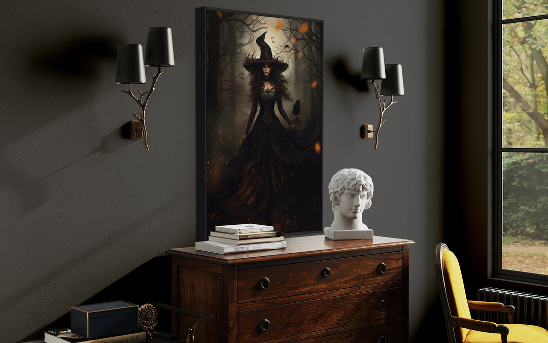 Gothic framed canvas wall art of a witch and raven in an enchanted forest above a wooden dresser.