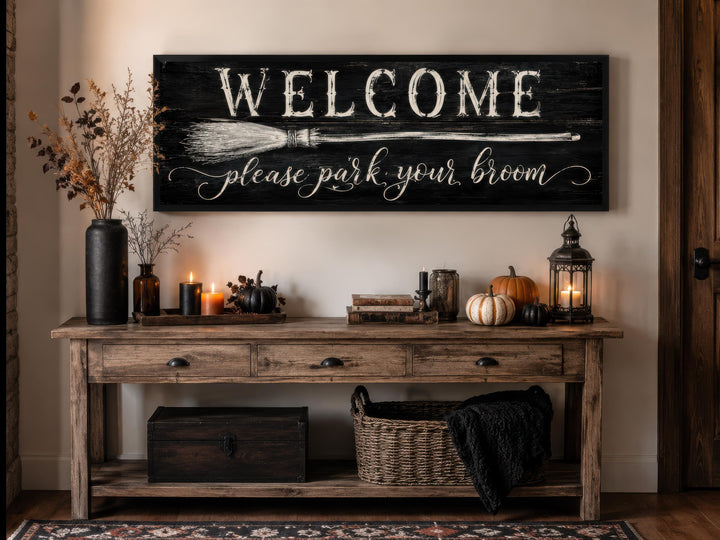 Witchy Halloween wall art sign with 'Welcome please park your broom' text above a console table.