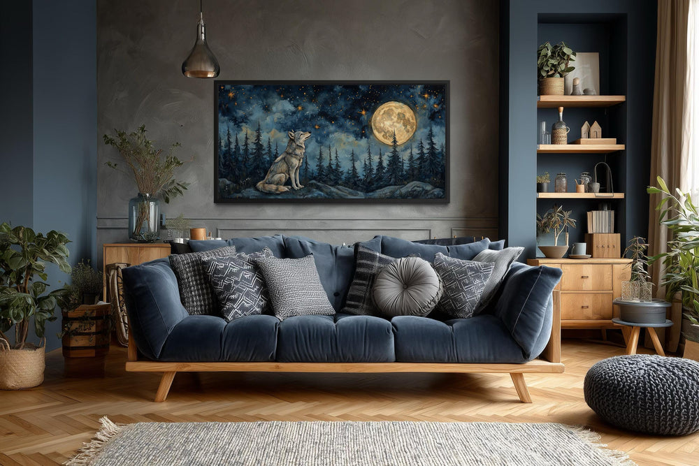 Horizontal canvas wall art of a wolf under a full moon in a night forest above a blue sofa.