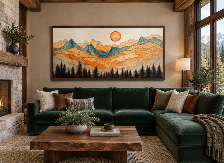 Rustic layered wood mountain wall art above a green velvet sectional in a cozy cabin living room.