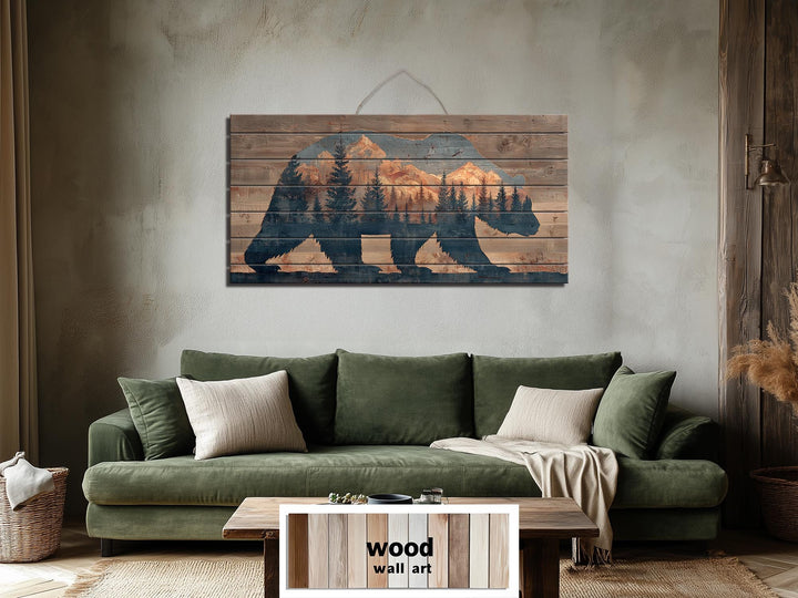 A wooden bear silhouette wall art piece featuring a mountain and forest scene on distressed planks.