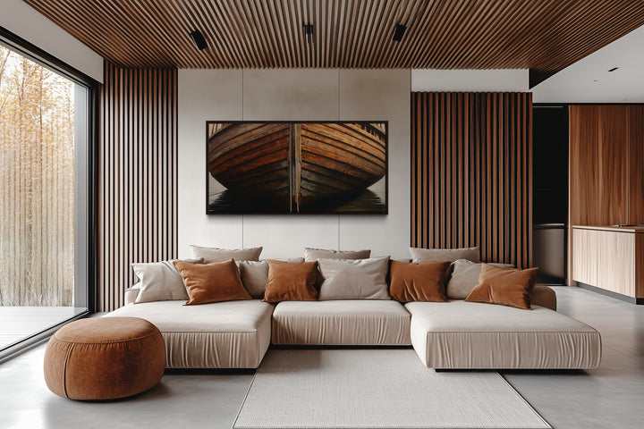 Framed wooden boat canvas print on a neutral wall above a modern sectional sofa in a rustic room.