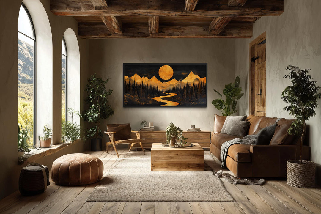 Framed canvas wall art of a wooden mountain river under a glowing moon in a rustic living room.