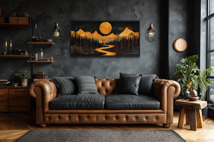 Framed canvas wall art of a golden mountain river and moon landscape in a rustic living room.