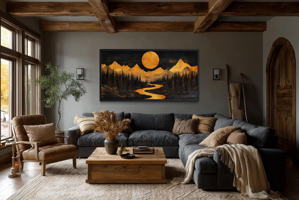 Framed canvas wall art of a golden moon and river over mountains in a rustic cabin living room.