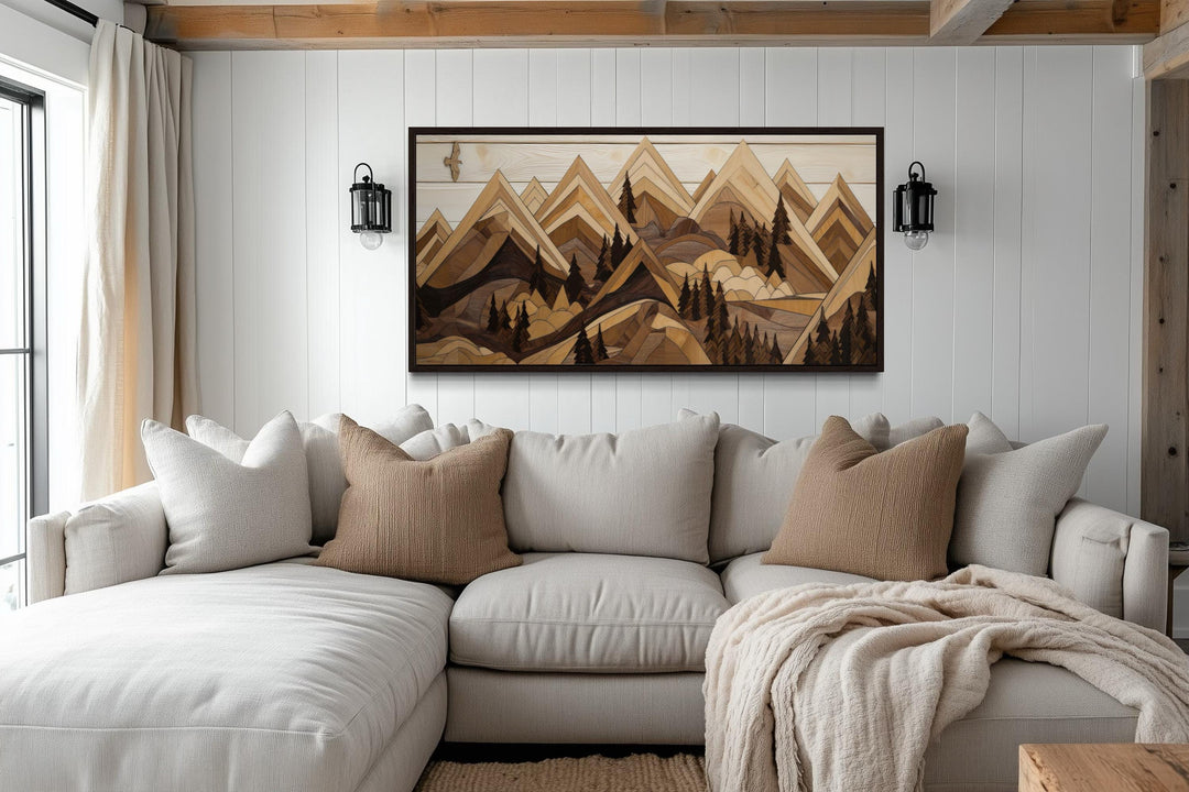 Wooden mountain with eagle framed canvas wall art above a beige sectional sofa in a rustic room.