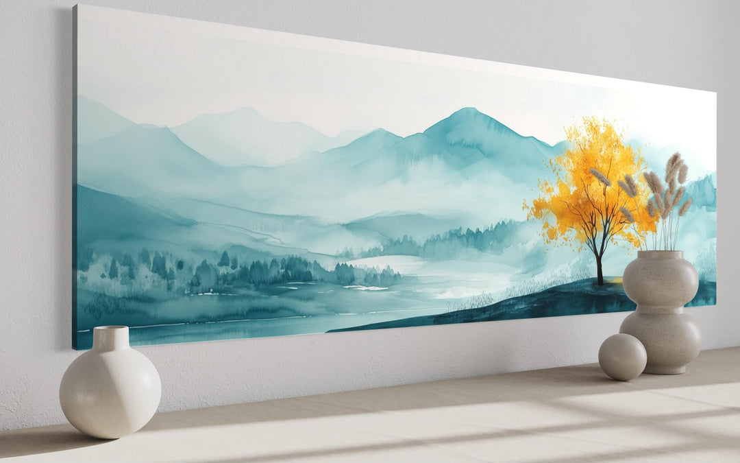 Long horizontal wall art of a golden yellow tree against a misty teal mountain landscape.