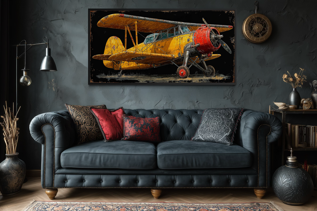 Yellow vintage biplane framed canvas wall art displayed above a dark tufted leather sofa.