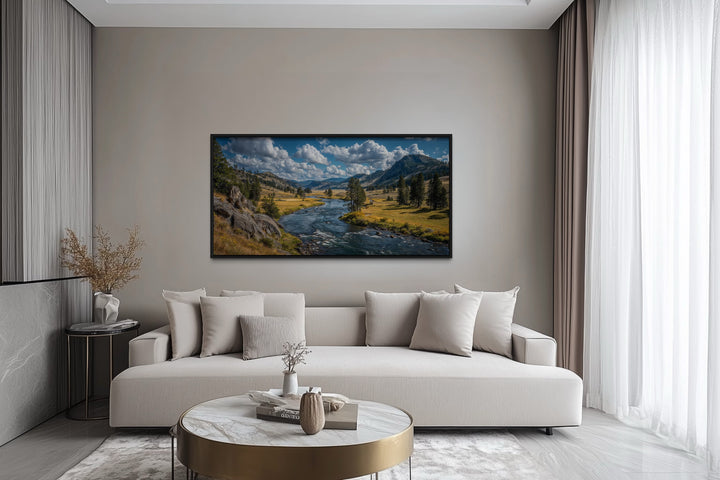 Framed panoramic canvas of Yellowstone National Park landscape above a modern sofa in a living room.