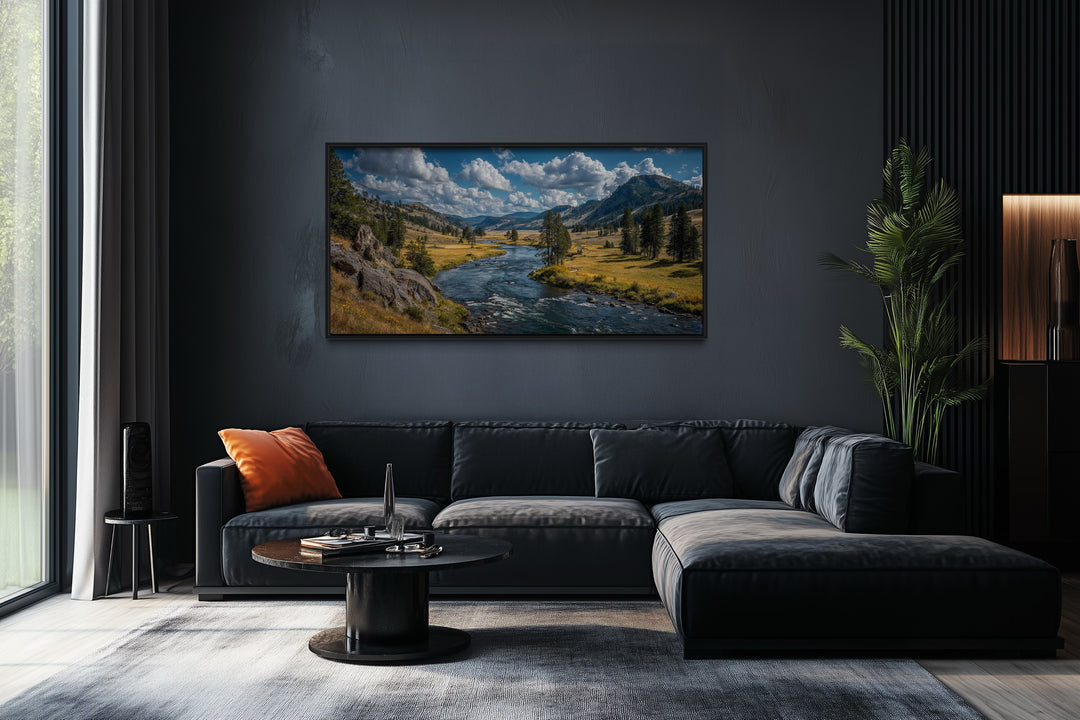 Framed panoramic canvas of Yellowstone National Park landscape hanging above a dark grey sofa.