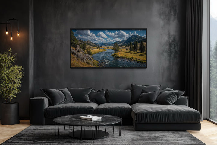 Panoramic framed canvas of Yellowstone National Park landscape above a modern black sofa.