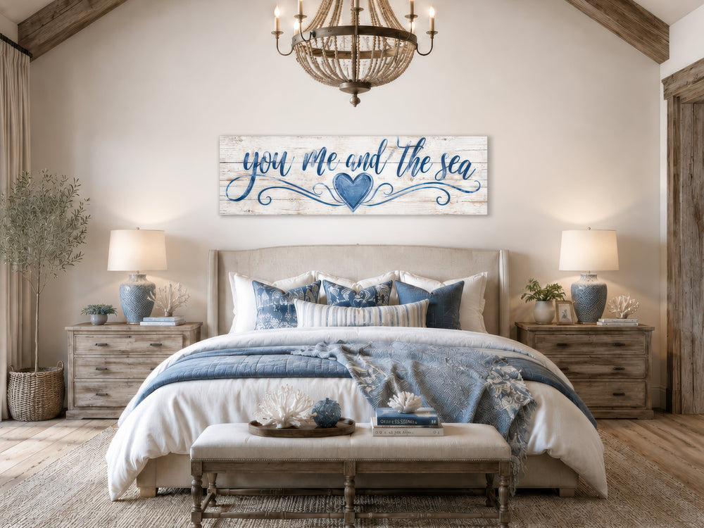 You Me And The Sea wall art in a coastal master bedroom above a bed with blue and white bedding.