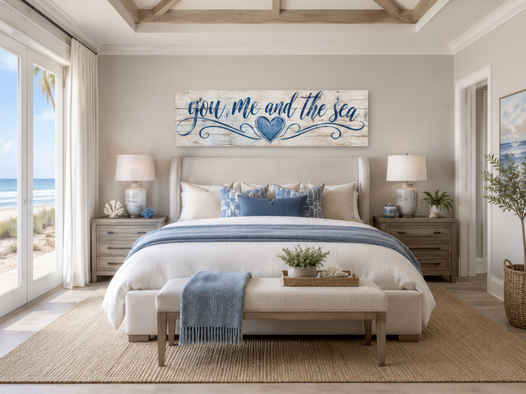 You Me And The Sea wall art above a bed in a coastal master bedroom with blue and white decor.