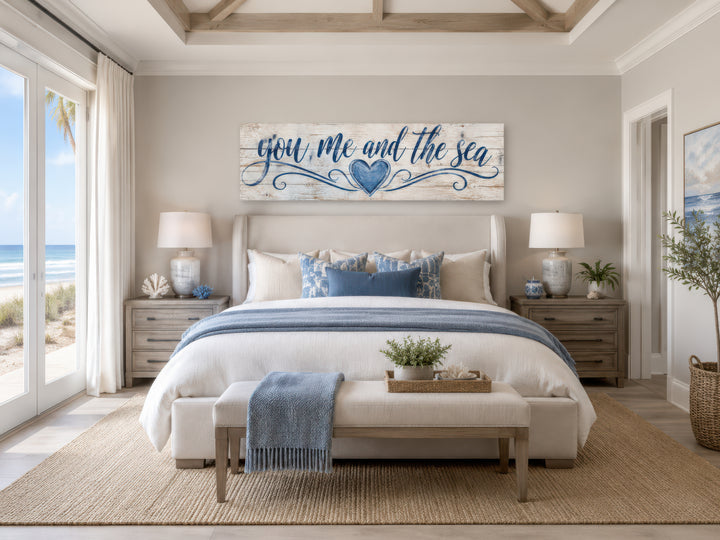 You Me And The Sea wall art above a bed in a coastal master bedroom with blue and white decor.